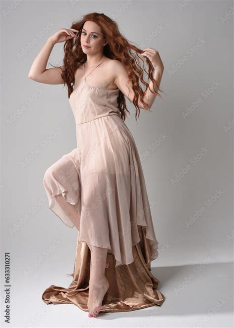 Full Length Portrait Of Beautiful Female Model With Long Brunette Hair Wearing A Creamy Pink