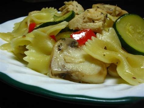 A White Plate Topped With Pasta Covered In Sauce And Veggies Next To