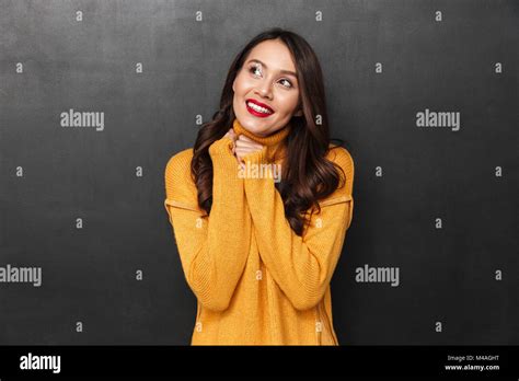 Pleased Brunette Woman In Sweater Posing And Looking Up Over Black Background Stock Photo Alamy