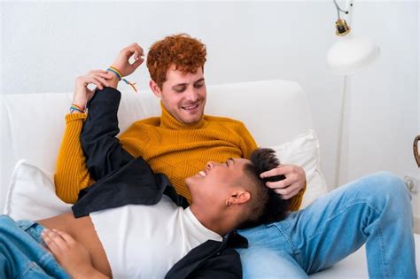 Hermosa pareja gay siendo romántica en casa en el sofá Foto Premium
