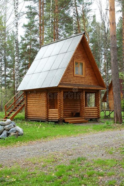 A Small Log Cabin In The Woods With Stairs Leading Up To It And Green