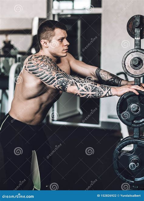Male Bodybuilder with a Tattoo on His Arm Standing in the Gym Stock