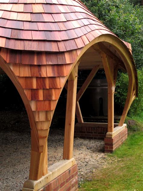 A Wooden Gazebo Sitting On Top Of A Lush Green Field Next To A Forest