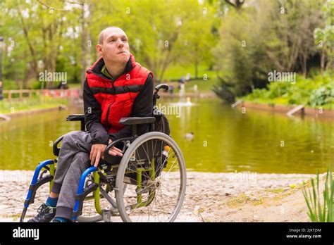 Portrait Of A Paralyzed Young Man In A Public Park In The City Sitting