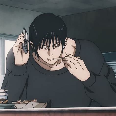 A Man Sitting At A Table With Food In Front Of Him And Holding A Cell