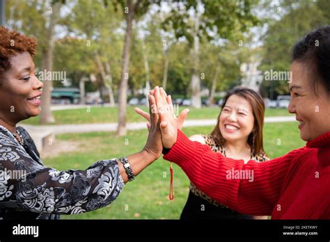 Three Mature Women With Joined Hands Smiling In A Public Park Stock Photo Alamy