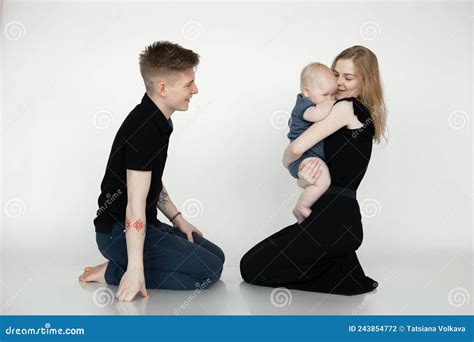 Famille Blonde Souriante Et Heureuse Assise Sur Le Genou En Studio Tenant Un Enfant En Armes