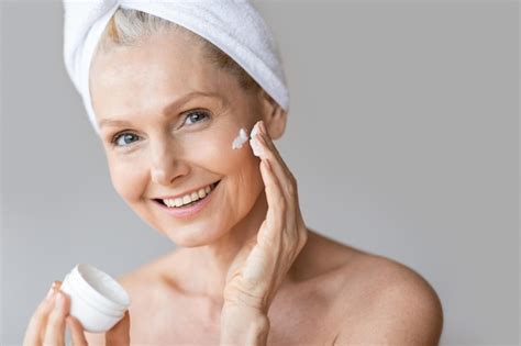 Premium Photo Beautiful Mature Woman Applying Moisturizing Cream Under Her Eyes Making Beauty