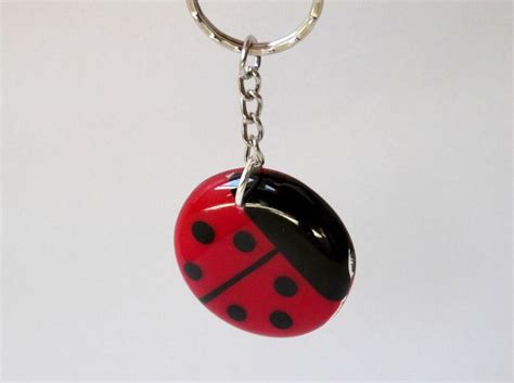 A Red And Black Ladybug Keychain Hanging From A Metal Ring On A White