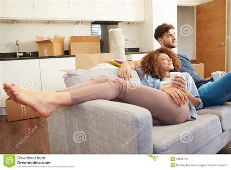 Couple Relaxing On Sofa With Hot Drink In New Home Stock Photo Image Of Drink Excitement