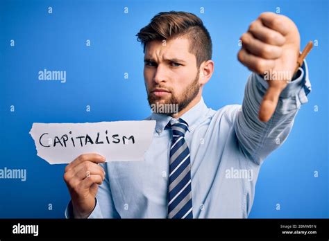 Junge blonde Geschäftsmann mit Bart und blauen Augen halten Papier mit Kapitalismus Nachricht