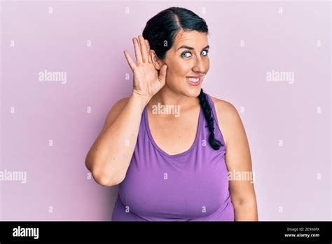 Plus Size Brunette Woman Wearing Sportswear Smiling With Hand Over Ear Listening And Hearing To