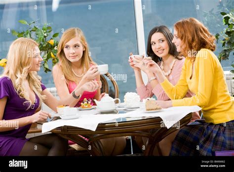 Portrait Of Four Young Women Sitting At The Table In The Cafe Stock