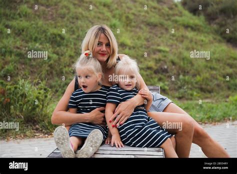 Une Jeune Fille Blonde Excit E Est Assise Sur Un Banc En B Ton Dans Le Parc Avec Sa M Re Et Sa