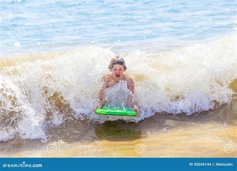 El Muchacho Se Divierte Que Practica Surf En Las Ondas Foto De Archivo