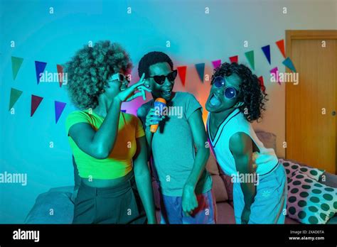 Multiracial Friends Partying At Night Singing Karaoke At Home With Blue