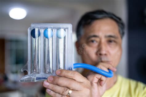 Old Man Uses A Tri Ball Incentive Spirometer For Check His Lung