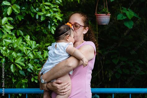 Aunt Red Haired Latina Woman Kissing Her Baby Girl Niece Outside In Nature Stock Photo Adobe Stock