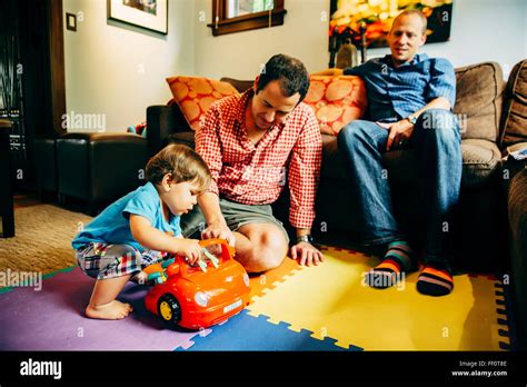 Gay Fathers Playing With Baby Son In Living Room Stock Photo Alamy