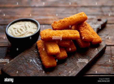 Pile Of Golden Fried Fish Fingers With White Garlic Sauce Stock Photo