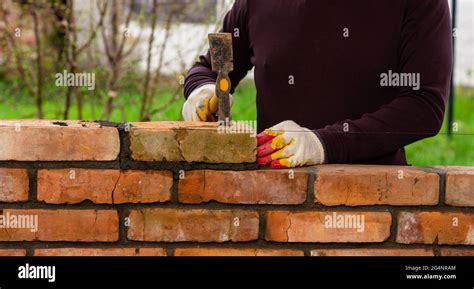 Un Hombre Construye Una Pared De Ladrillo Pone Un Ladrillo En Un