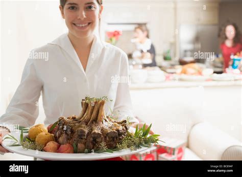 Young Woman Serving Rack Of Pork For Christmas Stock Photo Alamy