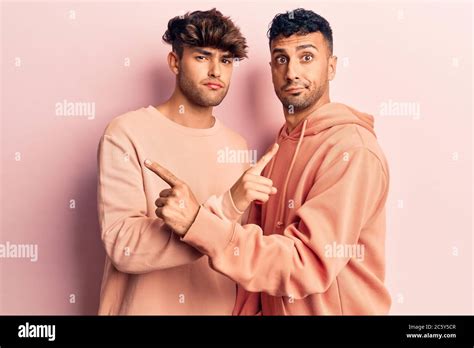 Jeune gay couple portant des vêtements décontractés pointant des deux côtés avec les doigts