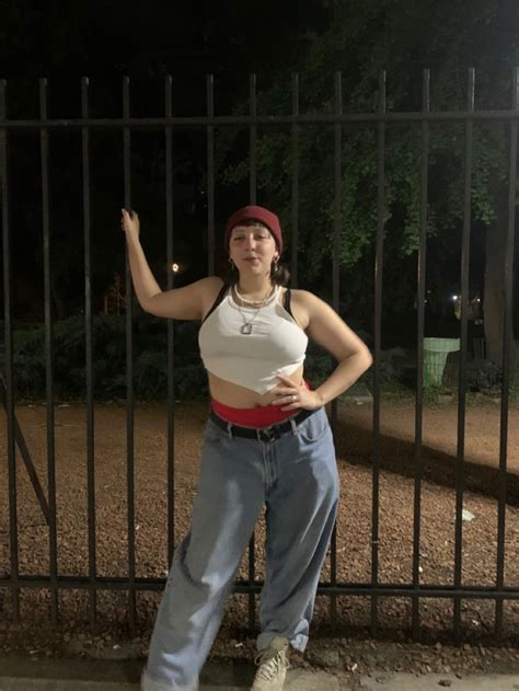 A Woman Standing In Front Of A Fence At Night