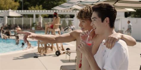 Two Men Standing Next To Each Other Near A Swimming Pool