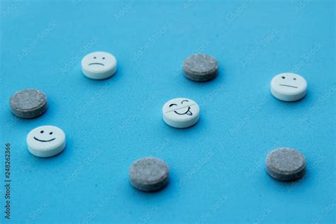 белые и коричневые таблетки и смешные лица в блистере на синем фоне ...