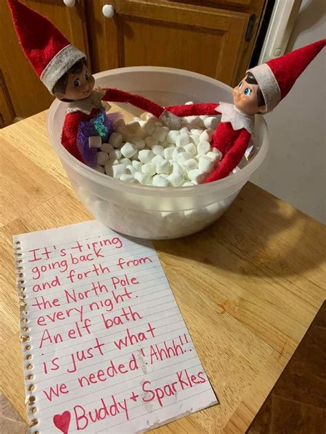 Two Elfs Are Sitting In A Bowl With Marshmallows On The Table