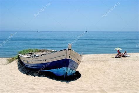 Old Rowing Boat On White Sandy Beach And Sunbathing Next Stock Photo