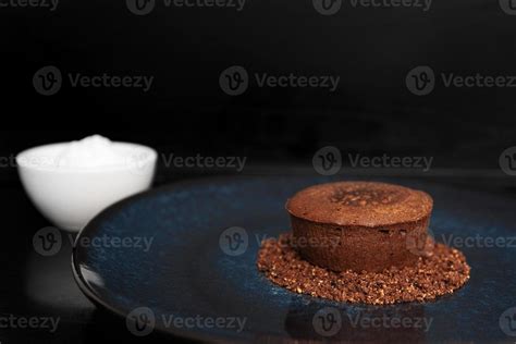 Chocolate Volcano Dessert On A Blue Plate Next To Ice Cream On A Black