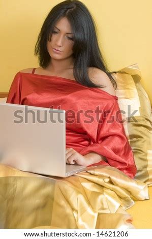 Attractive Brunette Working With Laptop On Her Bed Wearing A Red