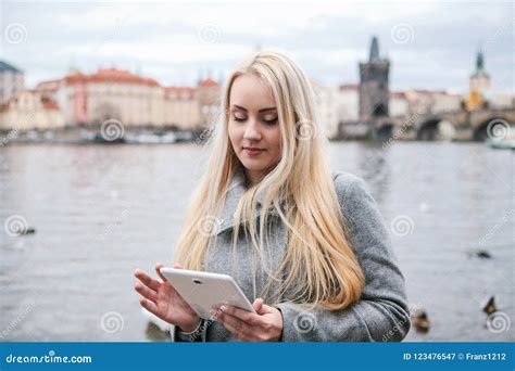Une Belle Fille Blonde Dans Un Manteau Utilise Un Comprim Image Stock Image Du Message