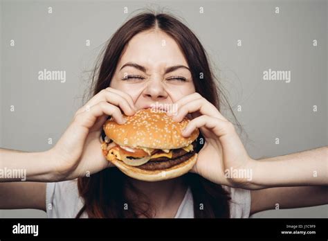 Mujer comiendo hamburguesa con queso fotografías e imágenes de alta