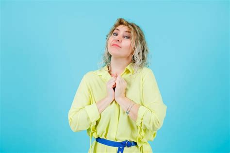 Heureuse Femme Blonde Regarde La Cam Ra En Tenant Les Poings Sur La Poitrine Sur Fond Bleu