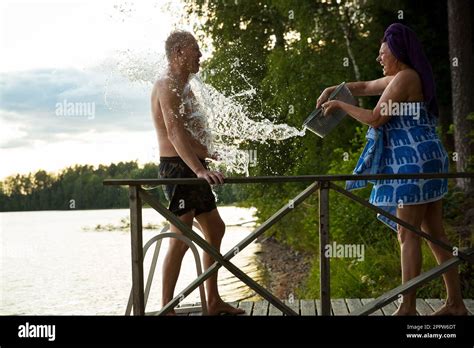 Aged Couple Having Fun After Finnish Sauna On Wooden Cottage Pier In A Lake Mature Woman