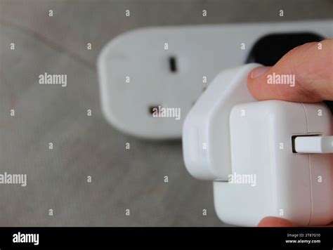 A Photo Of Someone Plugging In An Electrical Smartphone Charger Plug