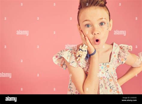 Portrait Of Brunette Girl Wearing Frilly Dress With Floral Pattern On Pink Background Looking