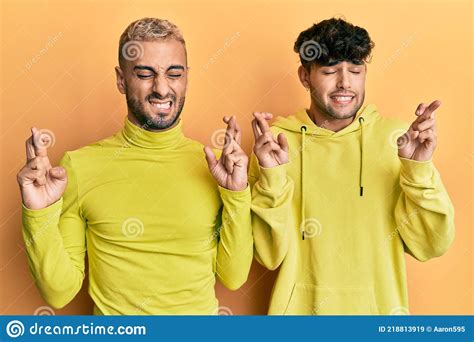 Homosexual Gay Pareja De Pie Juntos Usando Ropa Amarilla Gestos Dedo Cruzado Sonriendo Con