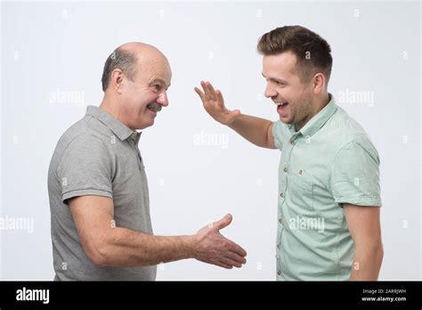 Two Mature Caucasian Men Father And Son Shaking Hands Making An Agreement Studio Shot Stock