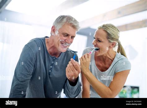 Freshening Up Together A Mature Man Shaving His Face While His Wife Brushes Her Teeth In The