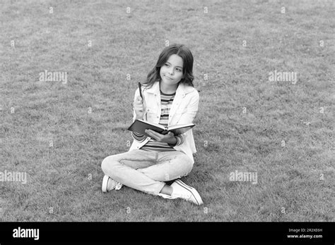 Thoughtful Teen Child Making Notes In Notebook Sitting On Grass Taking