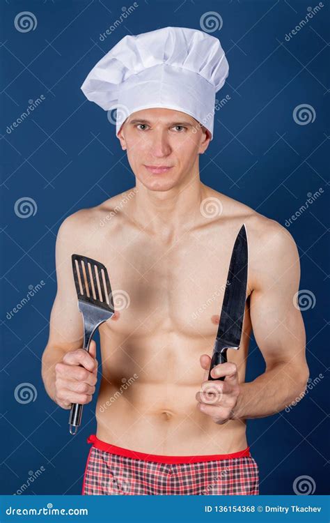 Handsome Chef In An Hat And Apron On Naked Muscular Body With Knife And Kitchen Utensils Stock
