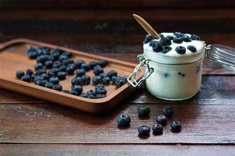 Ar Ndanos Frescos Con El Yogur En Vidrio En Las Tablas De Madera Foto