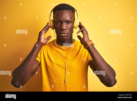 African American Man Listening To Music Using Headphones Over Isolated