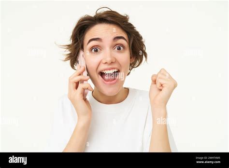 Portrait Of Amazed Brunette Girl Looks Surprised While Talks On Mobile Phone Answers A Call