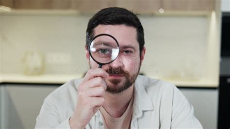 Unshaved Brunette Man Looking At Camera Through Magnifier And Raising Brow Stock Footage Video