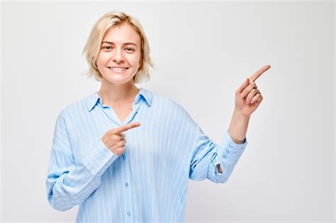 Jeune Femme Blonde En Tenue Décontractée Pointant Le Doigt De Côté Démontrant Un Espace Vide